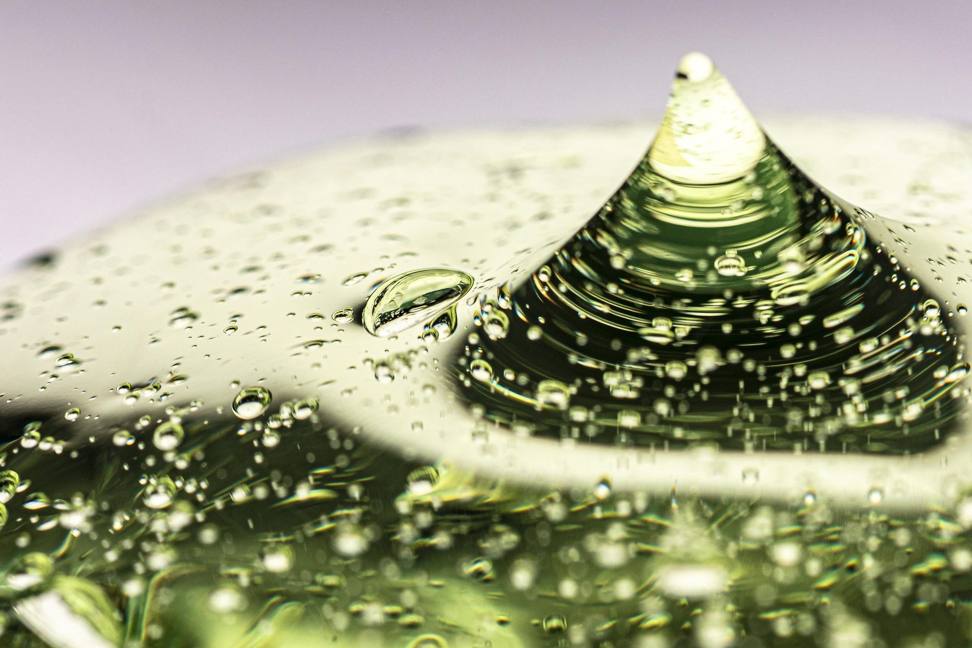 Clear pale green gel rising into a peak, full of tiny air bubbles, close up