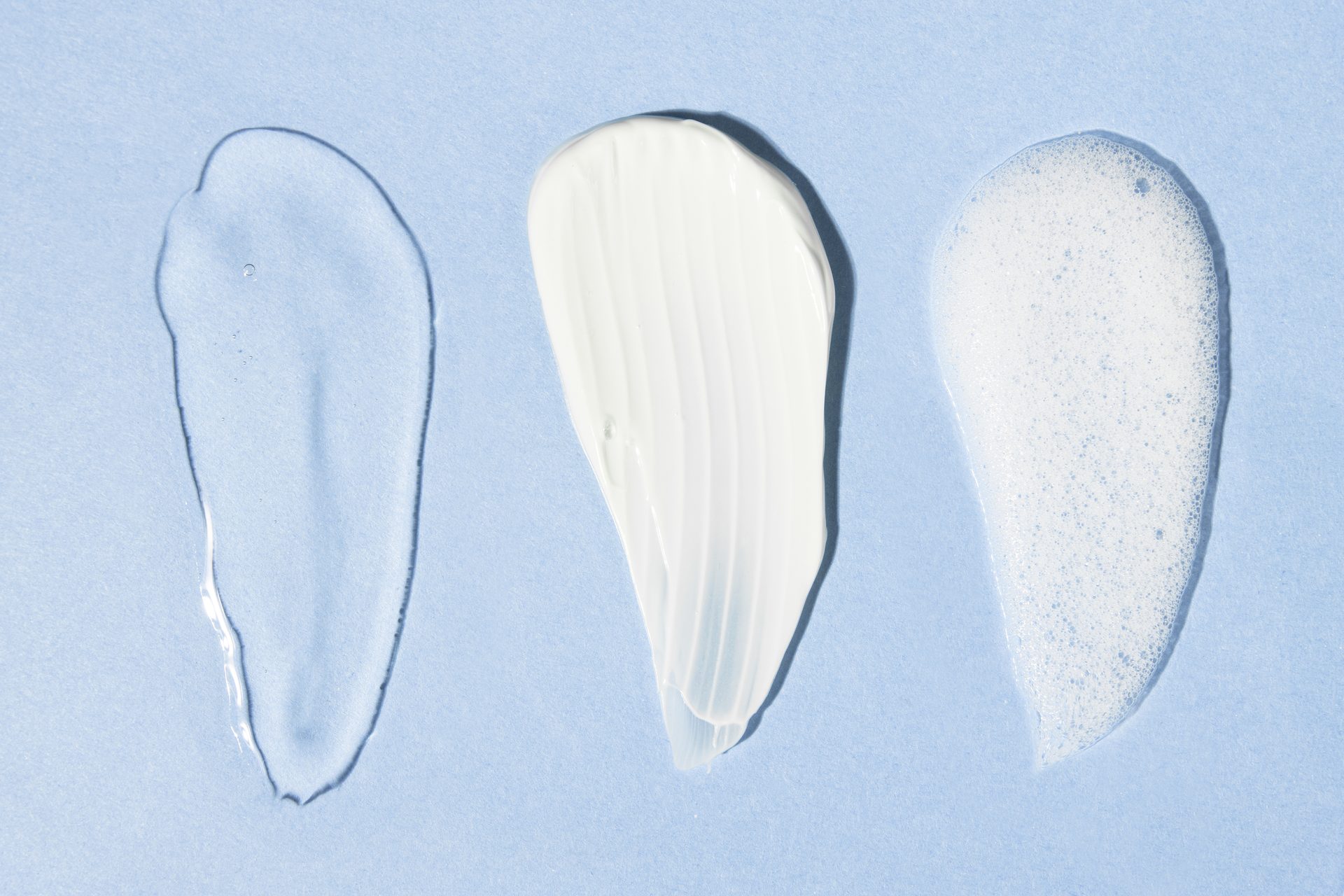 Three swatches on pale blue: clear gel, white cream and white foam side by side